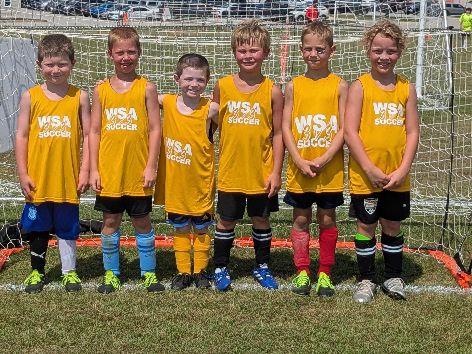 Young WSA team in yellow jerseys lined up in front of the net